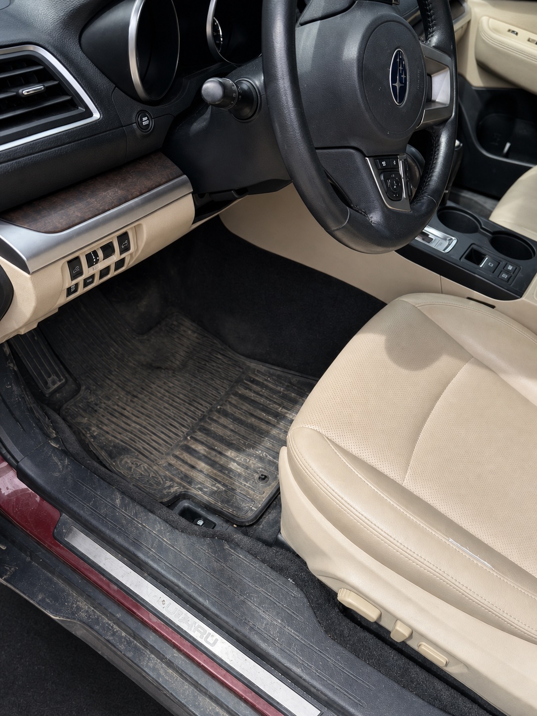 Driver footwell before an interior detail, with visible dirt on the floor mat